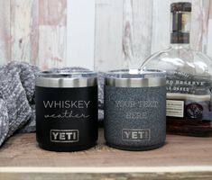 two personalized yeti tumblers sitting next to a bottle of whiskey