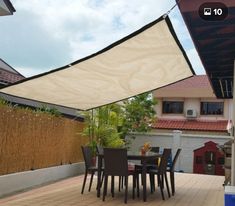 an outdoor dining area with table and chairs under a large shade sail on the roof