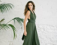 a woman standing in front of a white brick wall wearing a green dress and heels