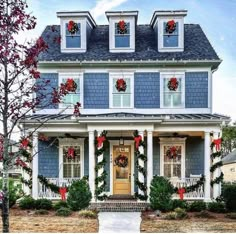 a house decorated for christmas with wreaths on the front porch and red bows hanging from the roof