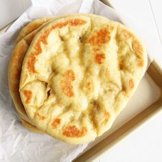 two flat breads sitting on top of each other in a tray with wax paper