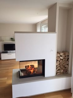 a fire place in the middle of a room with wood stacked on top of it