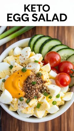 an egg salad in a bowl with tomatoes, cucumbers and green onions on the side