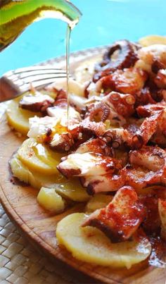 someone is drizzling sauce over some food on a wooden plate next to a pool