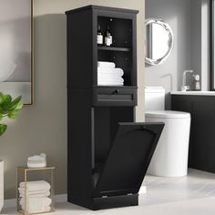 a white toilet sitting next to a tall black cabinet in a bathroom under a mirror