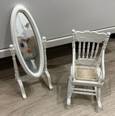 a white chair sitting next to a mirror on the floor