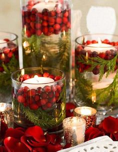 an image of christmas decorations in glass vases with candles on the side and red pomegranates around them