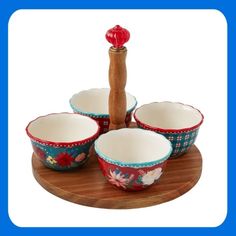 four bowls and a wooden spoon on a plate with a red pepper shaker in the middle