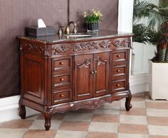 a bathroom vanity with marble top and carved wood design on the front, along with potted plants