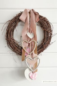 a heart shaped wreath hanging on the wall next to a door with a pink ribbon