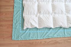 a blue and white quilted bed spread on top of a wooden floor next to a pair of scissors