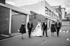 a bride and groom walking down the street with their bridal party in black and white