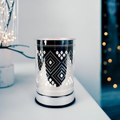 a black and white candle holder sitting on top of a table next to a christmas tree