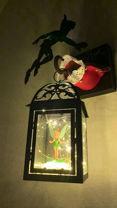 a light hanging from the side of a wall with a tinkerbell figure on it