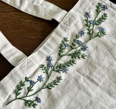 a white bag with blue flowers embroidered on it