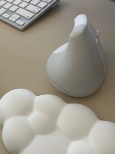 a white object sitting on top of a table next to a keyboard and computer mouse