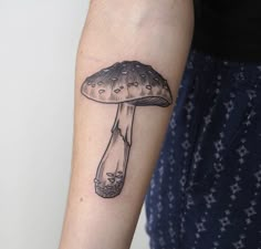 a mushroom tattoo on the left forearm and arm is shown in black ink with stars around it