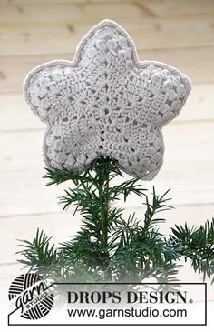 a crocheted snowflake decoration on top of a pine tree