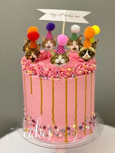 a pink birthday cake with cats on top