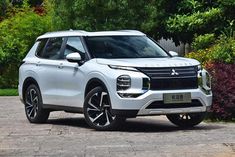 a white suv parked in front of some bushes