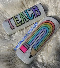 two glitter pencils with the words teach and rainbow on them sitting on a furry surface