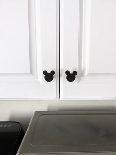 two black mickey mouse knobs on white cabinets