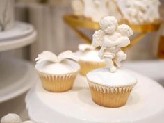 cupcakes with white frosting and angel figurines sitting on top of each other