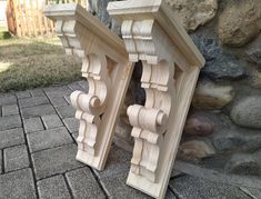 two wooden brackets on the ground next to a stone wall