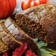 a loaf of pumpkin spice bread on a cutting board next to some leaves and apples