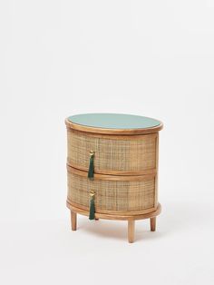 an oval wicker box with two drawers and green glass top, on wooden legs