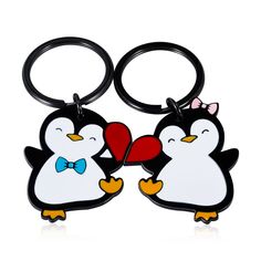 two black and white penguins holding a heart shaped keychain with one penguin wearing a bow tie