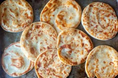 several flat breads on a baking sheet ready to be cooked in the oven for consumption