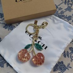 a key chain with two cherries hanging from it's end, in front of a box