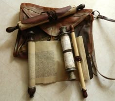 an old book with some writing on it next to two small telescopes and a leather bag