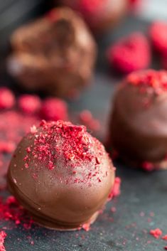 two chocolate truffles with red sprinkles on the top one is half eaten