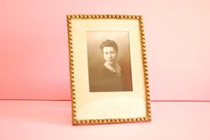 an old photo frame with a woman's face in it on a pink background