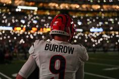 a football player wearing a red and white uniform looking out into the stadium at night