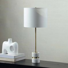 a white table lamp sitting on top of a wooden table next to a book and an elephant figurine