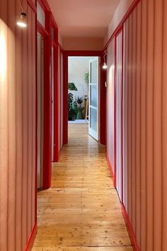 the hallway is lined with red partitions and white doors, along with wood flooring