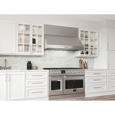 a kitchen with white cabinets and stainless steel stove top, oven hood over the range