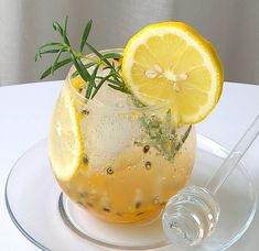 a drink with lemon and rosemary garnish in a glass on a white table