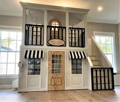 a dollhouse with black and white striped awnings on the front door, stairs to the second floor