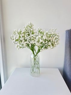 a glass vase filled with white flowers on top of a table