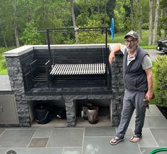 a man standing next to an outdoor grill