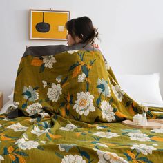 a woman wrapped in a blanket on top of a bed