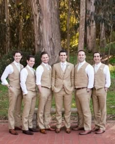 a group of men standing next to each other in front of a tree on a brick floor