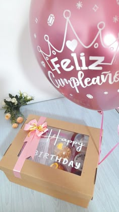 a pink balloon sitting next to a box with a birthday message on it and some flowers