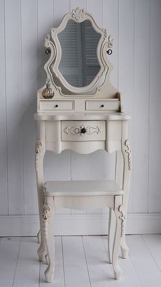 a white vanity with a mirror and bench in front of it on a white floor