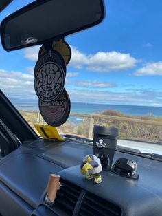 the interior of a car with a cup holder in the passenger side window, and an air freshener dispenser attached to the dash board