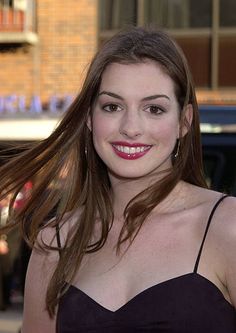 a woman with long brown hair wearing a strapless dress and smiling at the camera